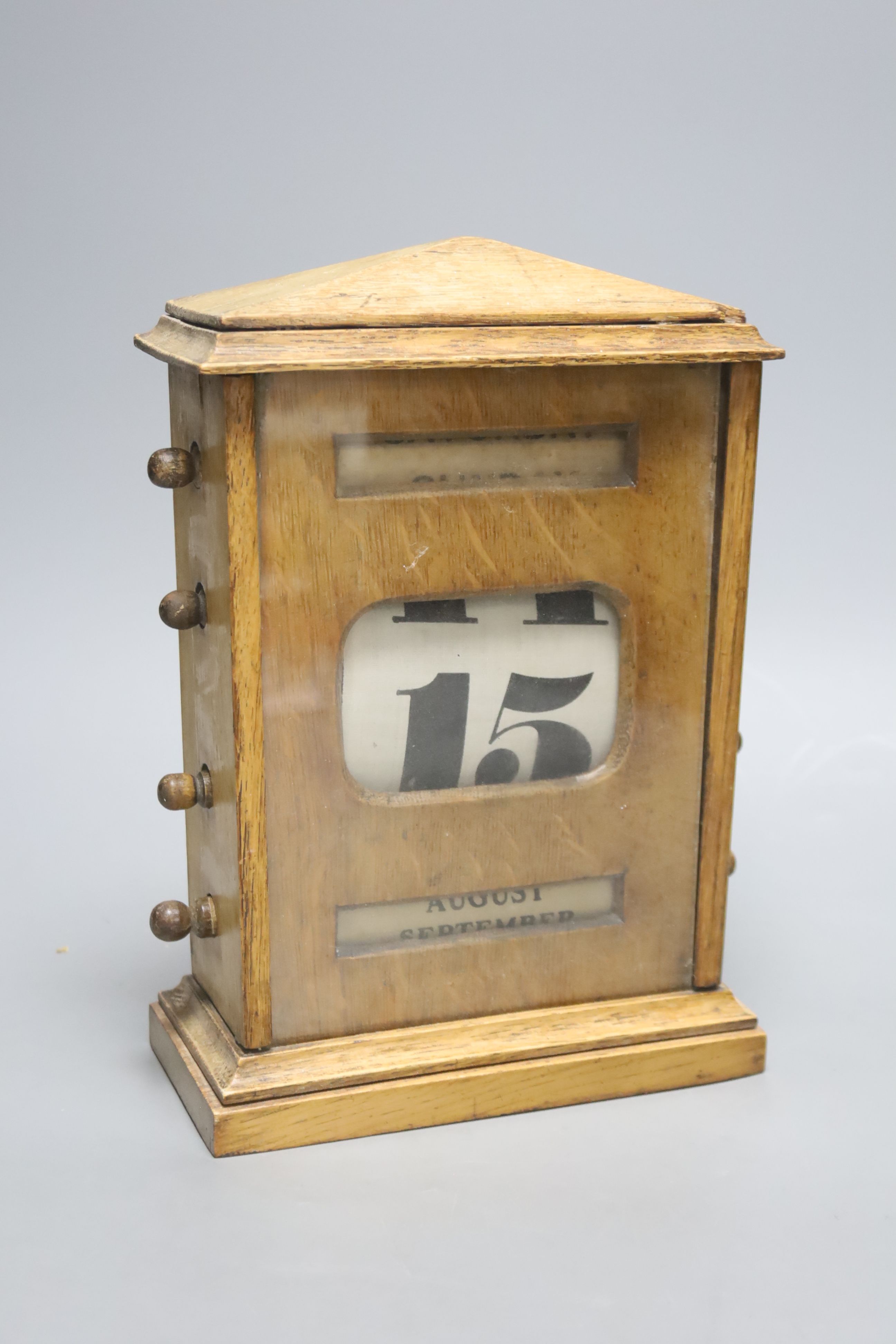 An early 20th century oak desk calendar with apertures, height 25cm